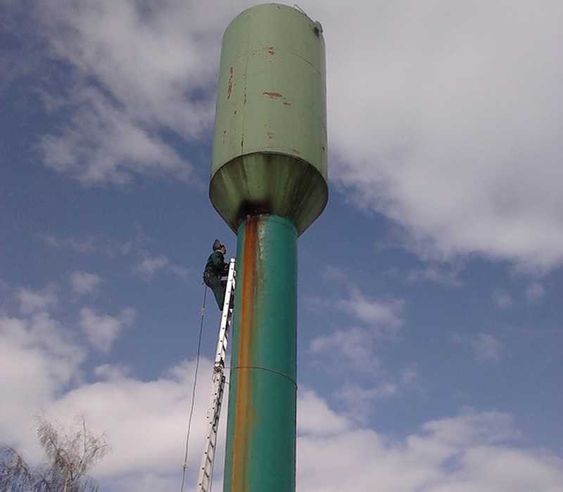 Промальпинист красит водонапорную металлическую водонапорную башню